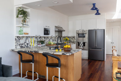 Mid-sized trendy u-shaped dark wood floor and brown floor eat-in kitchen photo in San Francisco with a drop-in sink, flat-panel cabinets, medium tone wood cabinets, marble countertops, multicolored backsplash, marble backsplash, stainless steel appliances, an island and multicolored countertops