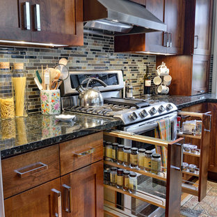 Ejemplo de cocina clásica con armarios estilo shaker, puertas de armario de madera en tonos medios, salpicadero multicolor, electrodomésticos de acero inoxidable y encimeras negras