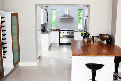 Example of a large trendy u-shaped eat-in kitchen design in Other with flat-panel cabinets, white cabinets, wood countertops, stainless steel appliances and an island