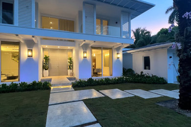 Inspiration for a large tropical white two-story stucco exterior home remodel in Miami with a metal roof and a brown roof