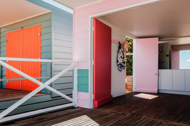 Photo of a small beach style one-storey pink exterior in Melbourne with wood siding.
