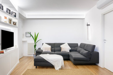 Foto di un piccolo soggiorno minimalista aperto con libreria, pareti bianche, pavimento in laminato e TV a parete