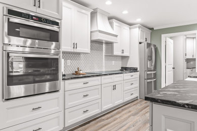 Modelo de cocina tradicional renovada con armarios estilo shaker, salpicadero blanco, salpicadero con mosaicos de azulejos, electrodomésticos de acero inoxidable y una isla