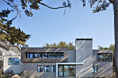 Cette photo montre une façade de maison grise moderne de taille moyenne et à un étage avec un revêtement mixte, un toit à quatre pans, un toit en métal et un toit gris.