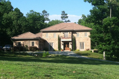 Large traditional beige three-story stone exterior home idea in Raleigh with a hip roof