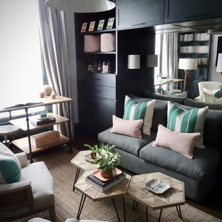 Large eclectic home office in London with a library, grey walls, dark hardwood floors, a standard fireplace, a plaster fireplace surround, a freestanding desk and brown floor.