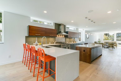 Inspiration for a large contemporary l-shaped open plan kitchen in Seattle with an undermount sink, flat-panel cabinets, dark wood cabinets, green splashback, glass tile splashback, stainless steel appliances, medium hardwood floors, with island, quartz benchtops, beige floor and white benchtop.