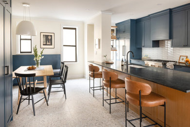 Kitchen - mid-sized transitional galley concrete floor and white floor kitchen idea in New York with an undermount sink, shaker cabinets, blue cabinets, soapstone countertops, white backsplash, ceramic backsplash, paneled appliances, an island and black countertops