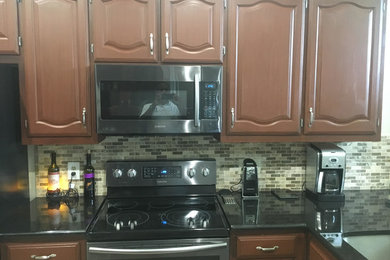 Mid-sized elegant l-shaped ceramic tile open concept kitchen photo in Dallas with a double-bowl sink, shaker cabinets, brown cabinets, solid surface countertops, gray backsplash, mosaic tile backsplash, stainless steel appliances and a peninsula