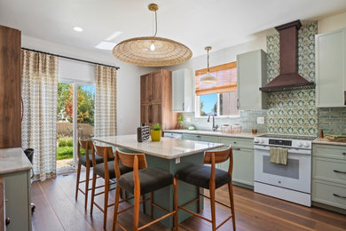 Inspiration for a mid-sized transitional u-shaped medium tone wood floor and brown floor enclosed kitchen remodel in Denver with a drop-in sink, green cabinets, green backsplash, cement tile backsplash, white appliances, an island and white countertops