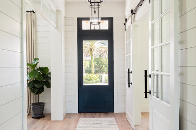 Beach style light wood floor, brown floor, wood ceiling and shiplap wall entryway photo in Tampa with white walls and a blue front door