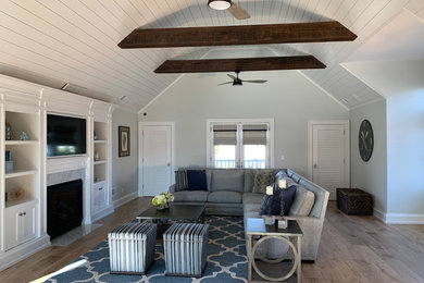Mid-sized beach style loft-style medium tone wood floor and brown floor family room photo in Other with blue walls, a standard fireplace and a media wall
