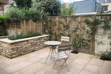 Photo of a small contemporary back full sun garden in Other with natural stone paving.