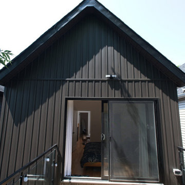 Dark Gabled Addition with Sliding Doors Opening onto a Wood Deck | East York