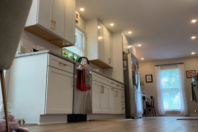 Inspiration for a mid-sized transitional galley light wood floor and brown floor eat-in kitchen remodel in Louisville with a double-bowl sink, shaker cabinets, white cabinets, granite countertops, white backsplash, subway tile backsplash, stainless steel appliances, no island and white countertops