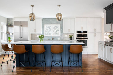 Eat-in kitchen - mid-sized transitional l-shaped dark wood floor and brown floor eat-in kitchen idea in Denver with a single-bowl sink, shaker cabinets, white cabinets, quartz countertops, gray backsplash, glass tile backsplash, stainless steel appliances, an island and white countertops