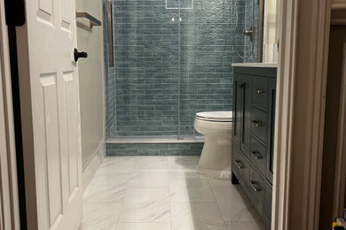 Large minimalist white tile and ceramic tile ceramic tile, white floor and double-sink sliding shower door photo in Philadelphia with shaker cabinets, gray cabinets, a two-piece toilet, white walls, an integrated sink, quartz countertops, white countertops, a niche and a freestanding vanity