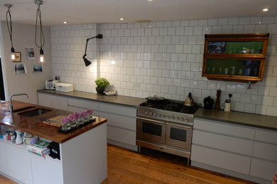 Design ideas for a small industrial galley kitchen/diner in Wiltshire with flat-panel cabinets, grey cabinets, concrete worktops, white splashback, ceramic splashback, stainless steel appliances and an island.