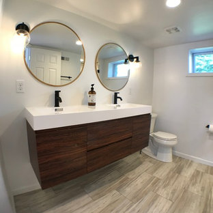 Immagine di una stanza da bagno padronale moderna di medie dimensioni con ante lisce, ante in legno scuro, WC monopezzo, piastrelle bianche, piastrelle diamantate, pareti bianche, pavimento in laminato, top in superficie solida e top bianco