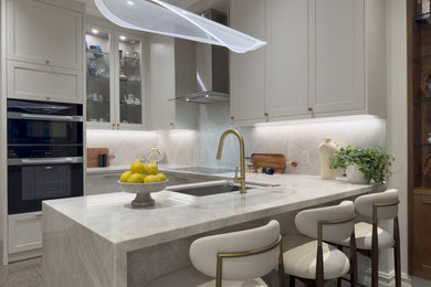 Example of a mid-sized transitional u-shaped eat-in kitchen design in Toronto with white cabinets, quartzite countertops, beige backsplash, an island and beige countertops