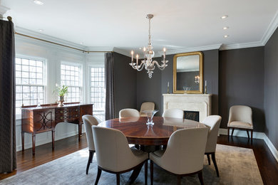 This is an example of a mid-sized traditional separate dining room in Minneapolis with grey walls, dark hardwood floors, a standard fireplace, a stone fireplace surround and brown floor.