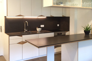 Idée de décoration pour une cuisine américaine design avec un plan de travail en quartz modifié, un sol en bois brun et îlot.