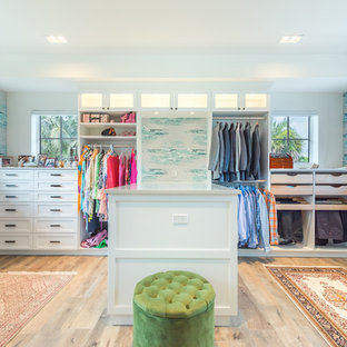 Inspiration for a tropical gender-neutral light wood floor walk-in closet remodel in Miami with white cabinets