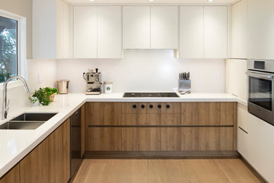 Example of a mid-sized minimalist medium tone wood floor eat-in kitchen design in Vancouver with flat-panel cabinets, light wood cabinets, quartzite countertops, white backsplash, quartz backsplash, stainless steel appliances, a peninsula and white countertops