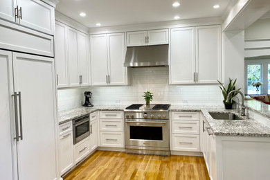 Inspiration for a large transitional u-shaped light wood floor and beige floor eat-in kitchen remodel in Tampa with an undermount sink, shaker cabinets, white cabinets, granite countertops, white backsplash, subway tile backsplash, stainless steel appliances, an island and multicolored countertops