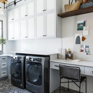 Diseño de cuarto de lavado en U, de estilo de casa de campo, de tamaño medio, con paredes blancas, lavadora y secadora juntas, encimeras blancas, armarios estilo shaker, puertas de armario grises y suelo gris