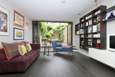 Idée de décoration pour un salon design de taille moyenne et ouvert avec une bibliothèque ou un coin lecture, un mur blanc, parquet foncé, aucune cheminée et un téléviseur indépendant.