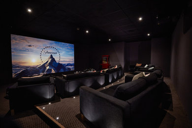 Large contemporary enclosed home cinema in Other with purple walls, carpet, a projector screen and multi-coloured floors.