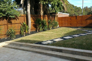 Large contemporary backyard patio in Sydney with natural stone pavers and no cover.