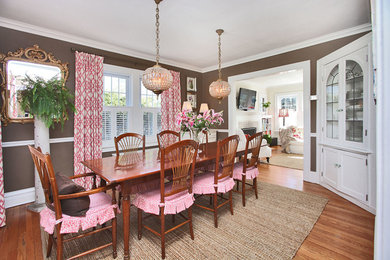 Example of a classic medium tone wood floor enclosed dining room design in New York with brown walls and no fireplace