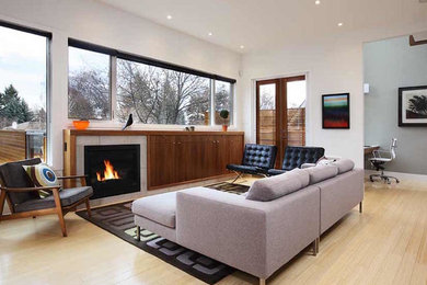 Large trendy open concept light wood floor living room photo in Calgary with white walls, a standard fireplace and a tile fireplace