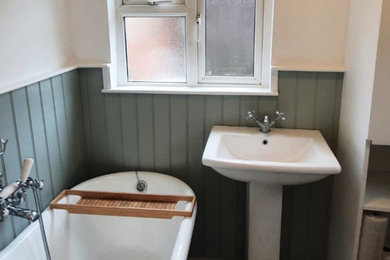 This is an example of a medium sized victorian ensuite bathroom in Berkshire with flat-panel cabinets, white cabinets, a freestanding bath, green walls, ceramic flooring, black floors, an open shower, a wall niche, a single sink, a freestanding vanity unit and panelled walls.