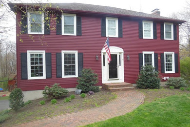 Mid-sized elegant red two-story vinyl house exterior photo in Boston with a clipped gable roof and a tile roof