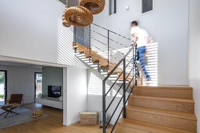 Idée de décoration pour un escalier design avec des marches en bois, des contremarches en bois et un garde-corps en métal.