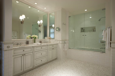 Inspiration for a large transitional master bathroom in Chicago with an undermount sink, recessed-panel cabinets, marble benchtops, an undermount tub, a shower/bathtub combo, a two-piece toilet, white tile, ceramic tile, grey walls, marble floors and white cabinets.