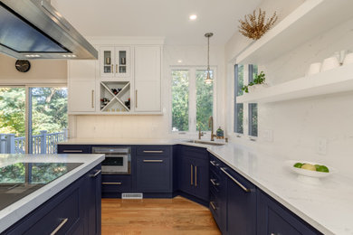 Kitchen - l-shaped medium tone wood floor kitchen idea in Boston with shaker cabinets, blue cabinets, quartz countertops, quartz backsplash, an island, an undermount sink and paneled appliances