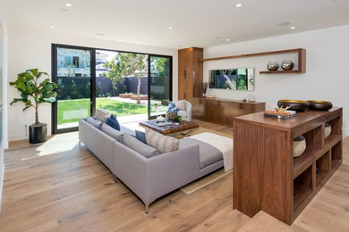 Photo of a large contemporary open concept living room in Los Angeles with white walls, medium hardwood floors, no fireplace and a built-in media wall.