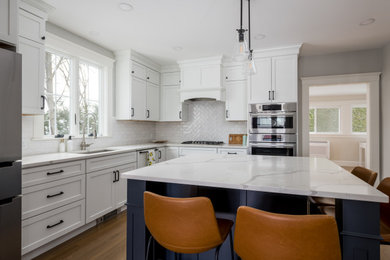 Kitchen - transitional l-shaped light wood floor kitchen idea in Boston with raised-panel cabinets, quartz countertops, white backsplash, cement tile backsplash, stainless steel appliances, an island and white countertops
