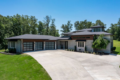 Example of a large minimalist two-story brick house exterior design in Little Rock with a shingle roof and a black roof