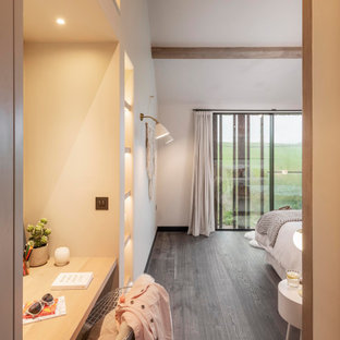Design ideas for a large scandinavian guest bedroom in Cornwall with beige walls, dark hardwood floors, no fireplace, brown floor, coffered and panelled walls.