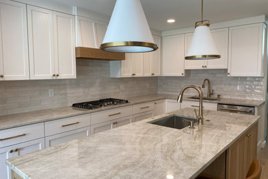 Transitional l-shaped light wood floor enclosed kitchen photo in Cleveland with an undermount sink, shaker cabinets, light wood cabinets, quartzite countertops, white backsplash, subway tile backsplash, stainless steel appliances, an island and beige countertops