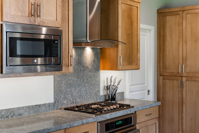 Example of a large transitional u-shaped medium tone wood floor and brown floor kitchen pantry design in Other with an undermount sink, shaker cabinets, medium tone wood cabinets, quartz countertops, gray backsplash, stainless steel appliances, a peninsula and gray countertops
