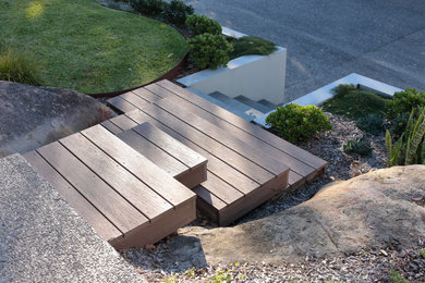 Large modern front yard xeriscape in Sydney with a retaining wall.