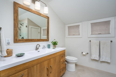 Walk-in shower - small 3/4 white tile and ceramic tile single-sink, ceramic tile and beige floor walk-in shower idea in Grand Rapids with flat-panel cabinets, light wood cabinets, quartz countertops, white countertops, a built-in vanity, a two-piece toilet, white walls, an integrated sink and a hinged shower door