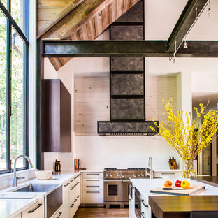 Design ideas for a large country galley kitchen pantry in Atlanta with a farmhouse sink, flat-panel cabinets, dark wood cabinets, limestone benchtops, white splashback, stone slab splashback, stainless steel appliances, medium hardwood floors, with island, brown floor and white benchtop.