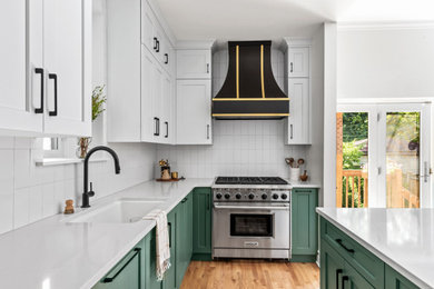 Example of a mid-sized classic u-shaped medium tone wood floor and brown floor eat-in kitchen design in Chicago with a drop-in sink, shaker cabinets, green cabinets, quartz countertops, white backsplash, ceramic backsplash, an island, white countertops and stainless steel appliances